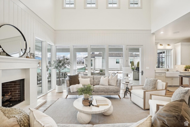 living room featuring light wood finished floors, a high ceiling, and a fireplace with raised hearth