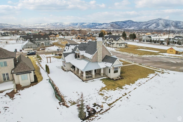 snowy aerial view featuring a residential view and a mountain view