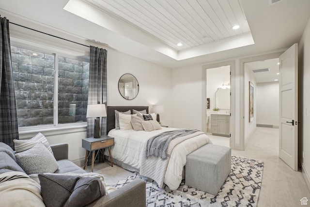 bedroom featuring ensuite bathroom, recessed lighting, light colored carpet, baseboards, and a tray ceiling