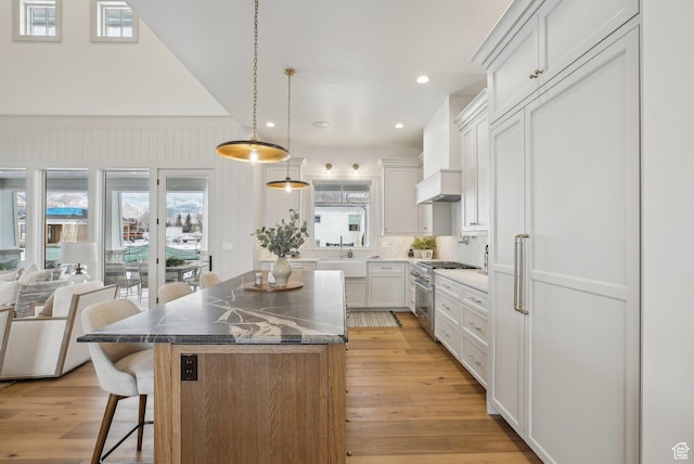 kitchen featuring a center island, white cabinetry, decorative light fixtures, and a kitchen bar