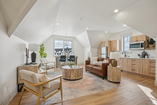 living area with light wood finished floors, baseboards, vaulted ceiling, and a wealth of natural light