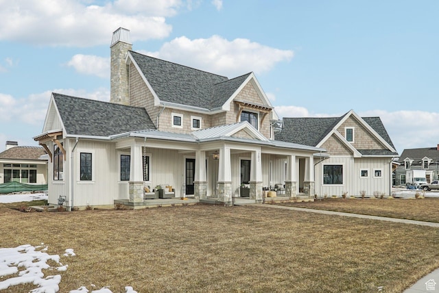 view of front of home with a shingled roof, a porch, board and batten siding, and a front yard