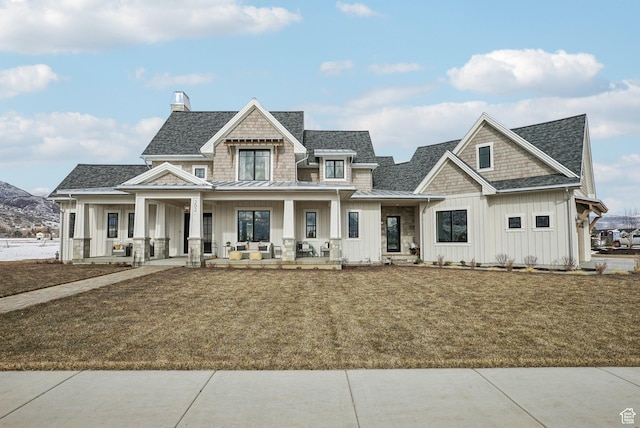 view of front of house with a porch, board and batten siding, a front yard, a standing seam roof, and metal roof