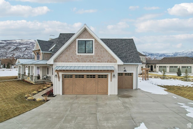view of front of home with a standing seam roof, a mountain view, covered porch, driveway, and board and batten siding