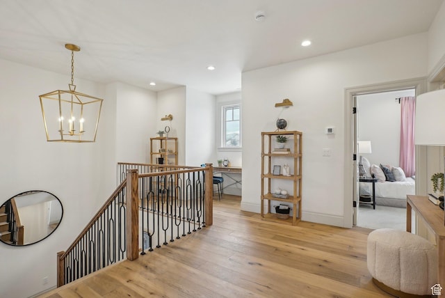 hallway with light wood-style flooring, a notable chandelier, recessed lighting, an upstairs landing, and baseboards