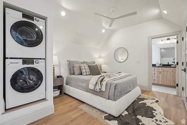 bedroom featuring ensuite bathroom, a ceiling fan, vaulted ceiling, stacked washing maching and dryer, and light wood finished floors