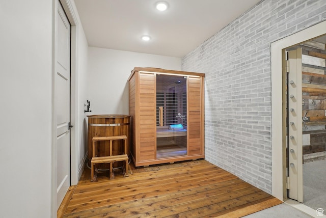 interior space with brick wall, wood finished floors, and recessed lighting