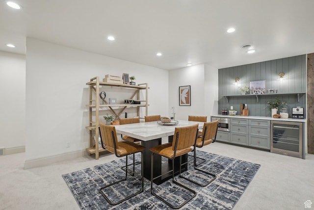 dining space with a dry bar, recessed lighting, wine cooler, and light colored carpet
