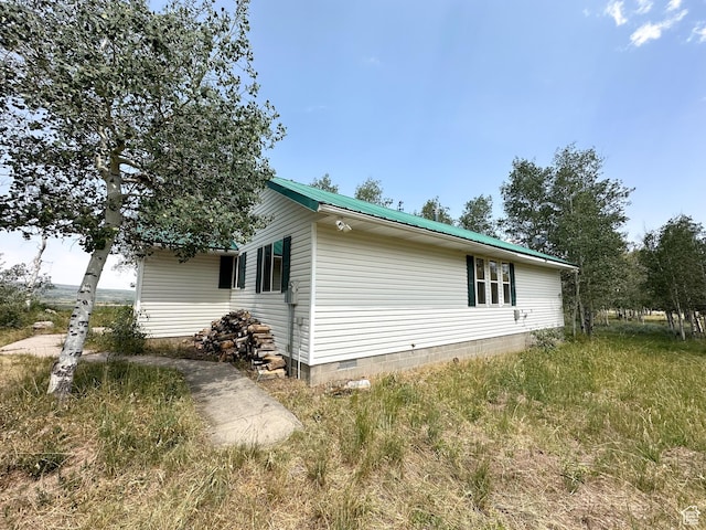 view of side of home featuring metal roof and crawl space