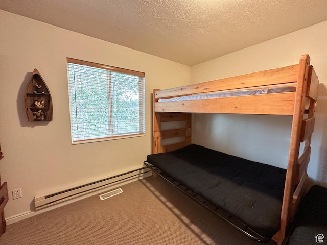 carpeted bedroom featuring baseboard heating and a textured ceiling