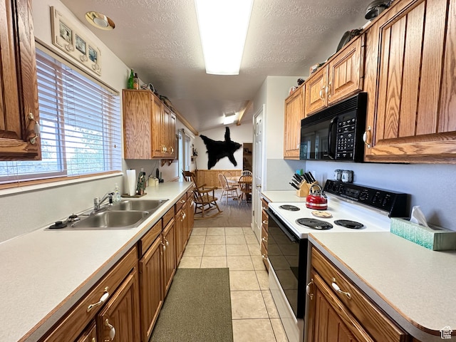 kitchen with electric range, brown cabinetry, light countertops, black microwave, and a sink