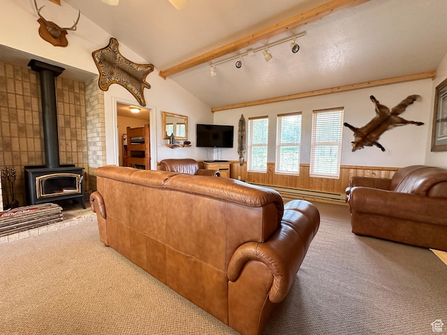 living area with vaulted ceiling with beams, a wood stove, baseboard heating, carpet, and rail lighting