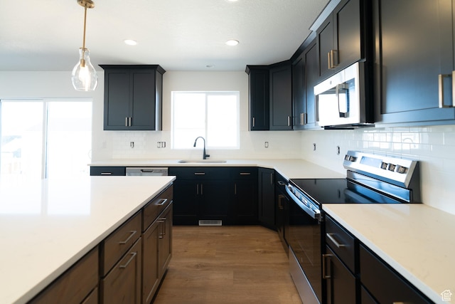 4111 N Ophir Dr, Eagle Mountain, UT 84005 - kitchen with stainless steel appliances, a sink, wood finished floors, decorative light fixtures, and backsplash