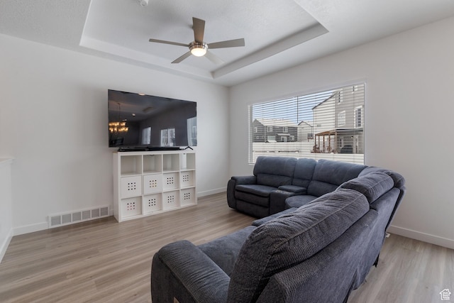 1033 E Bigelow Ave, Layton, UT 84040 - living room featuring visible vents, a tray ceiling, baseboards, light wood finished floors, and a ceiling fan