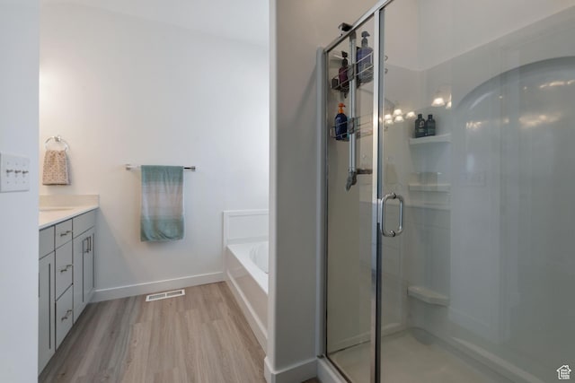 1033 E Bigelow Ave, Layton, UT 84040 - bathroom with a stall shower, visible vents, baseboards, a garden tub, and wood finished floors