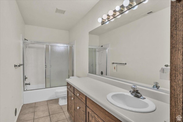 bathroom with tile patterned floors, vanity, toilet, and combined bath / shower with glass door