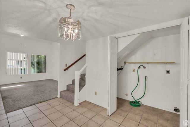 stairs with a textured ceiling, a chandelier, tile patterned flooring, and carpet