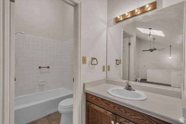 full bath with toilet, a skylight, tile patterned flooring, vanity, and vaulted ceiling