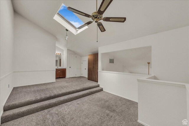 interior space with ceiling fan, a skylight, vaulted ceiling, and baseboards