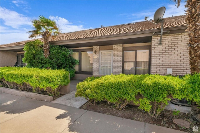property entrance with a tile roof and brick siding