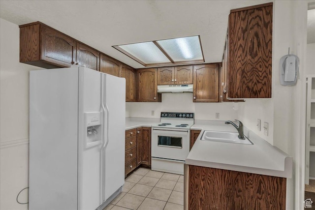 kitchen featuring white appliances, a sink, under cabinet range hood, light tile patterned floors, and light countertops