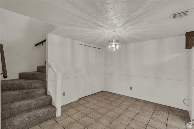 unfurnished dining area with stairs, a chandelier, light tile patterned floors, and a textured ceiling