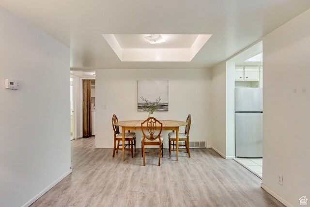4953 S Eastridge Ln E Unit 143, Salt Lake City, UT 84117 - dining room featuring light wood finished floors, a tray ceiling, visible vents, and baseboards
