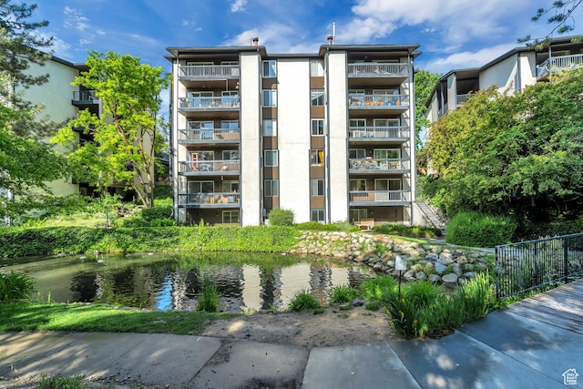 4953 S Eastridge Ln E Unit 143, Salt Lake City, UT 84117 - view of building exterior featuring a water view and fence