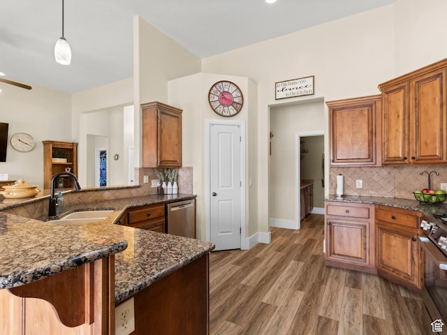 1908 S Yuma Dr, Washington, UT 84780 - kitchen featuring stainless steel appliances, brown cabinetry, tasteful backsplash, dark stone counters, and light wood-type flooring