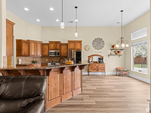 1908 S Yuma Dr, Washington, UT 84780 - kitchen with stainless steel appliances, a high ceiling, a kitchen bar, light wood-style flooring, and dark stone countertops