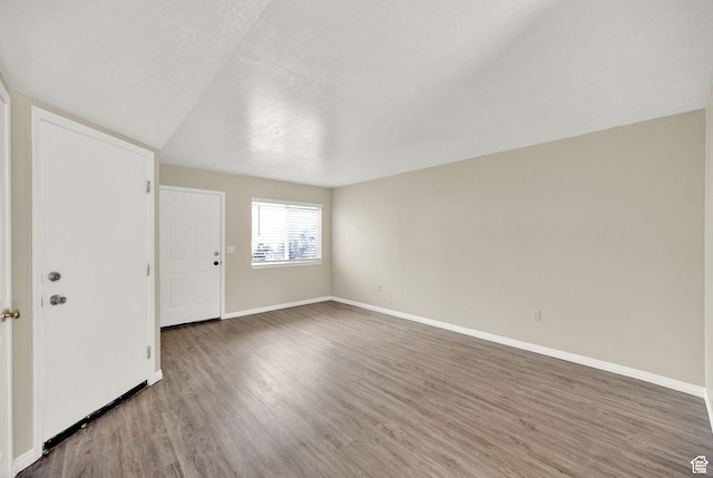 spare room featuring a textured ceiling, baseboards, and wood finished floors