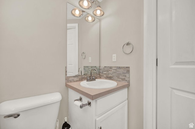 bathroom with vanity, backsplash, and toilet