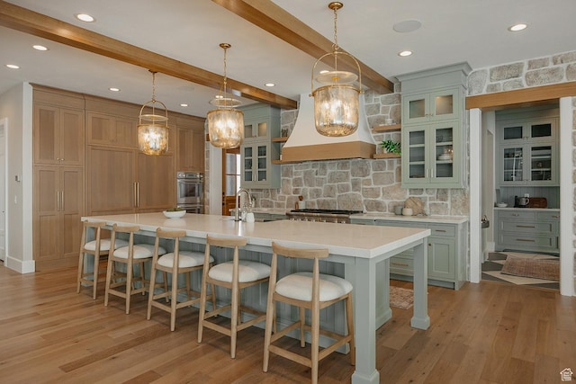 1685 W Midway Ln, Heber City, UT 84032 - kitchen featuring light wood-style flooring, a spacious island, backsplash, light countertops, and premium range hood
