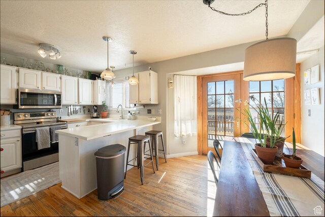 1446 E Murdock Dr S, Pleasant Grove, UT 84062 - kitchen with pendant lighting, light countertops, appliances with stainless steel finishes, white cabinets, and a kitchen bar
