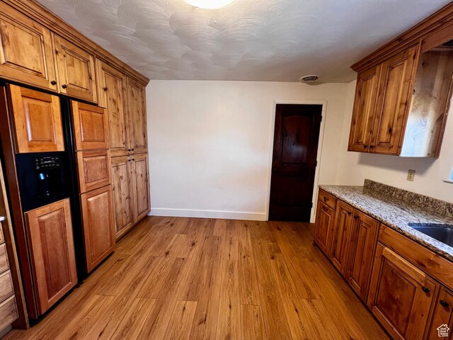 404 N 1st E, Grace, ID 83241 - kitchen with baseboards, brown cabinetry, light wood-style floors, and light stone counters