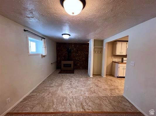 404 N 1st E, Grace, ID 83241 - interior space with baseboards, a wood stove, and a textured ceiling
