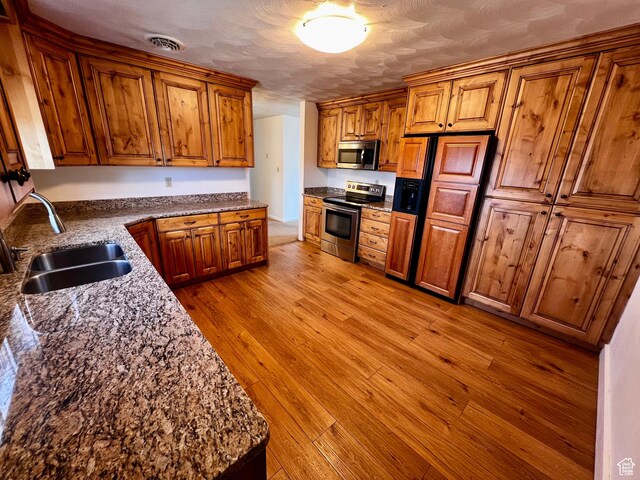 404 N 1st E, Grace, ID 83241 - kitchen with a sink, brown cabinets, light wood-style flooring, stainless steel appliances, and visible vents
