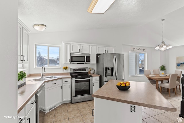 257 Rosewood Cir, Logan, UT 84321 - kitchen with white cabinets, a kitchen island, hanging light fixtures, stainless steel appliances, and a sink