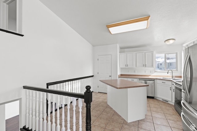 257 Rosewood Cir, Logan, UT 84321 - kitchen with stainless steel appliances, a sink, a kitchen island, white cabinetry, and light countertops