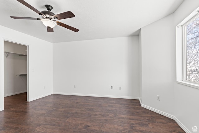 257 Rosewood Cir, Logan, UT 84321 - unfurnished bedroom featuring a ceiling fan, a spacious closet, baseboards, and dark wood-style flooring