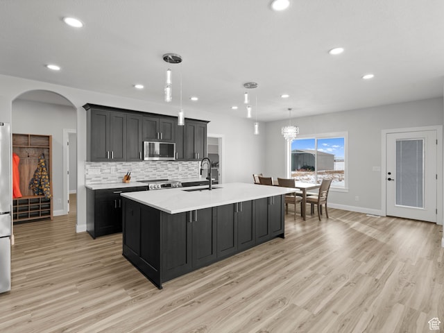 8345 W 11050 N, Tremonton, UT 84337 - kitchen with light countertops, stainless steel microwave, backsplash, a sink, and light wood-style flooring