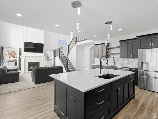 8345 W 11050 N, Tremonton, UT 84337 - kitchen with light countertops, a center island with sink, stainless steel appliances, light wood-style floors, and decorative backsplash