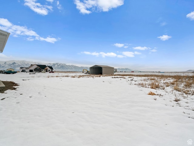 8345 W 11050 N, Tremonton, UT 84337 - yard covered in snow with an outbuilding, a mountain view, and a storage shed
