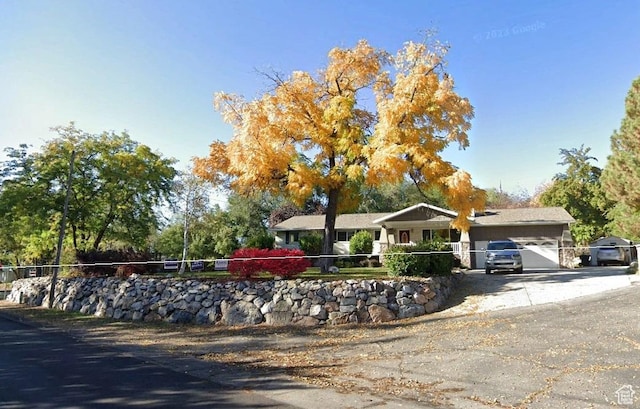ranch-style home featuring driveway, an attached garage, and fence