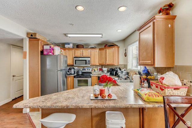 3842 S Clare Dr Unit D-1, West Valley City, UT 84119 - kitchen featuring a breakfast bar area, stainless steel appliances, a peninsula, light countertops, and decorative backsplash