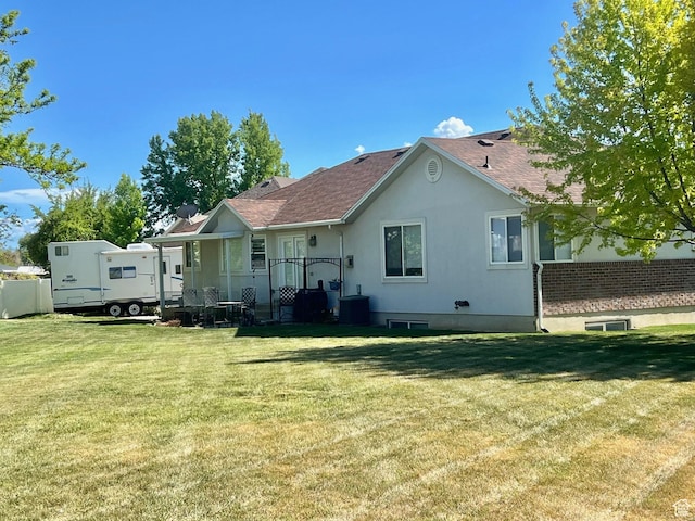 back of property with a yard, roof with shingles, and central air condition unit