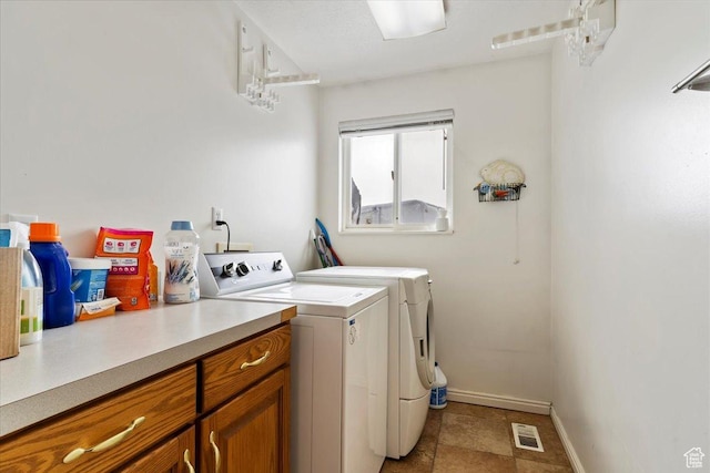 clothes washing area featuring independent washer and dryer, baseboards, and cabinet space