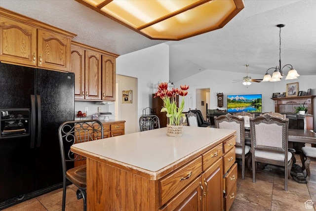 kitchen with black refrigerator with ice dispenser, a kitchen island, a chandelier, brown cabinetry, and lofted ceiling
