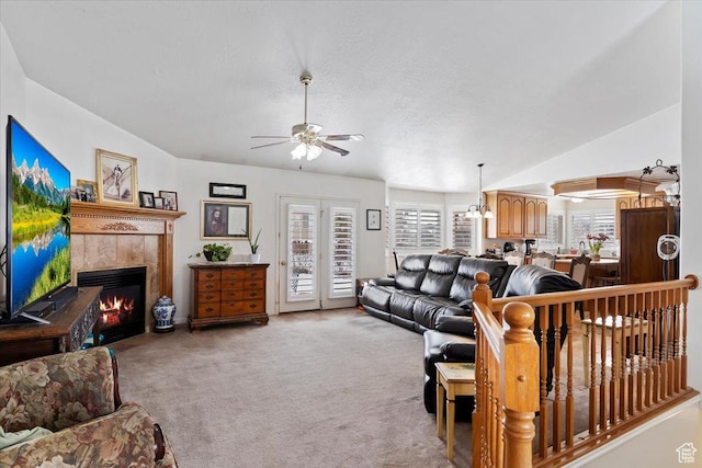 living area featuring ceiling fan, light colored carpet, a tile fireplace, and lofted ceiling