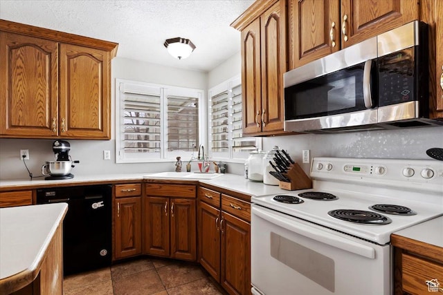 kitchen featuring white electric range, stainless steel microwave, dishwasher, light countertops, and a sink